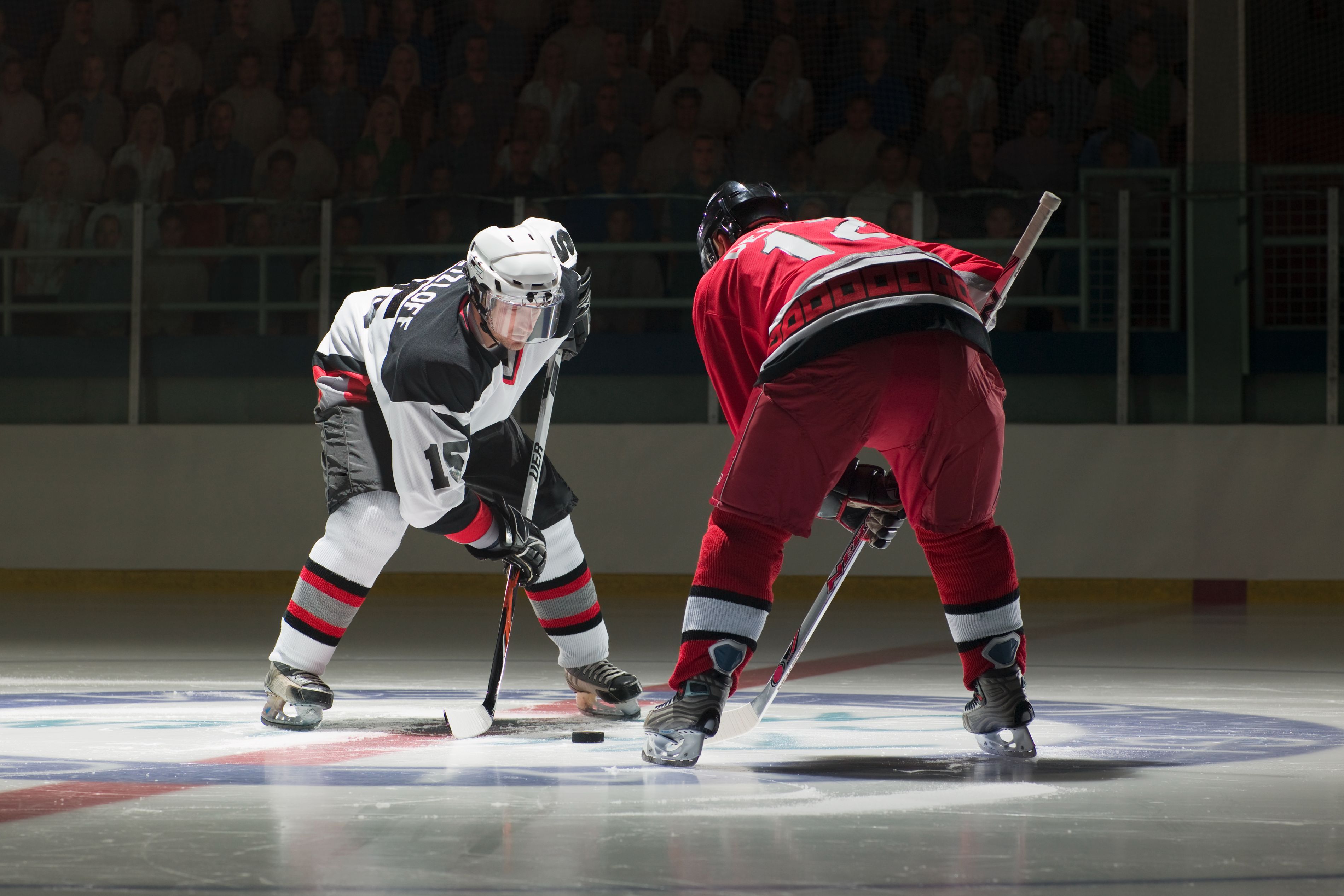 Two hockey players facing off at an ice rink