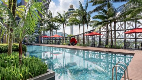 Palm-fringed outdoor swimming pool at Crowne Plaza Changi Airport with modern glass architecture in the background