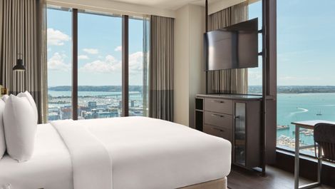 Bright, contemporary hotel room at Hotel Indigo Auckland with harbour views through floor-to-ceiling windows