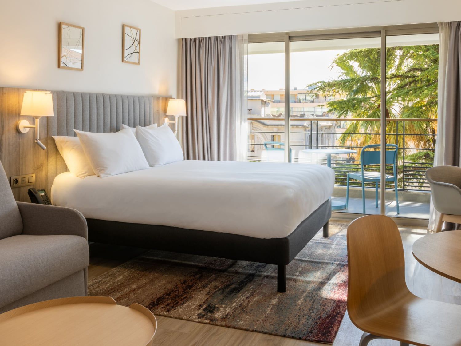 Bright hotel room with balcony overlooking trees