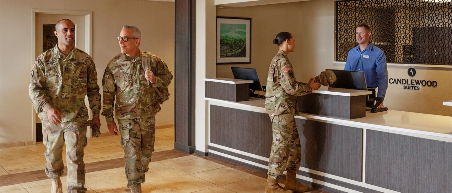 Service members walking in hotel lobby, female service member speaking with front desk clerk.