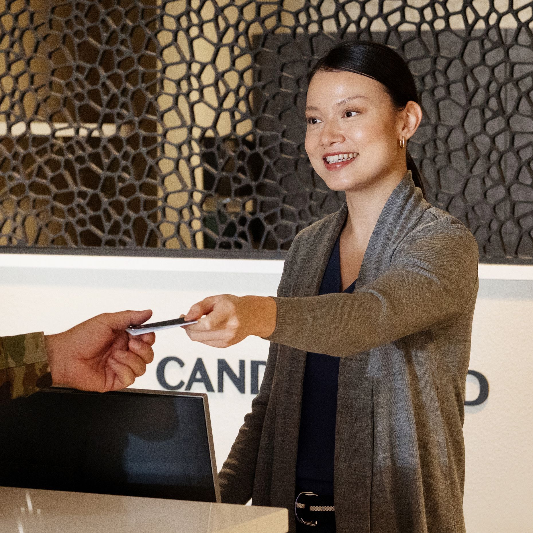 Hotel front desk clerk hands key card to service member guest