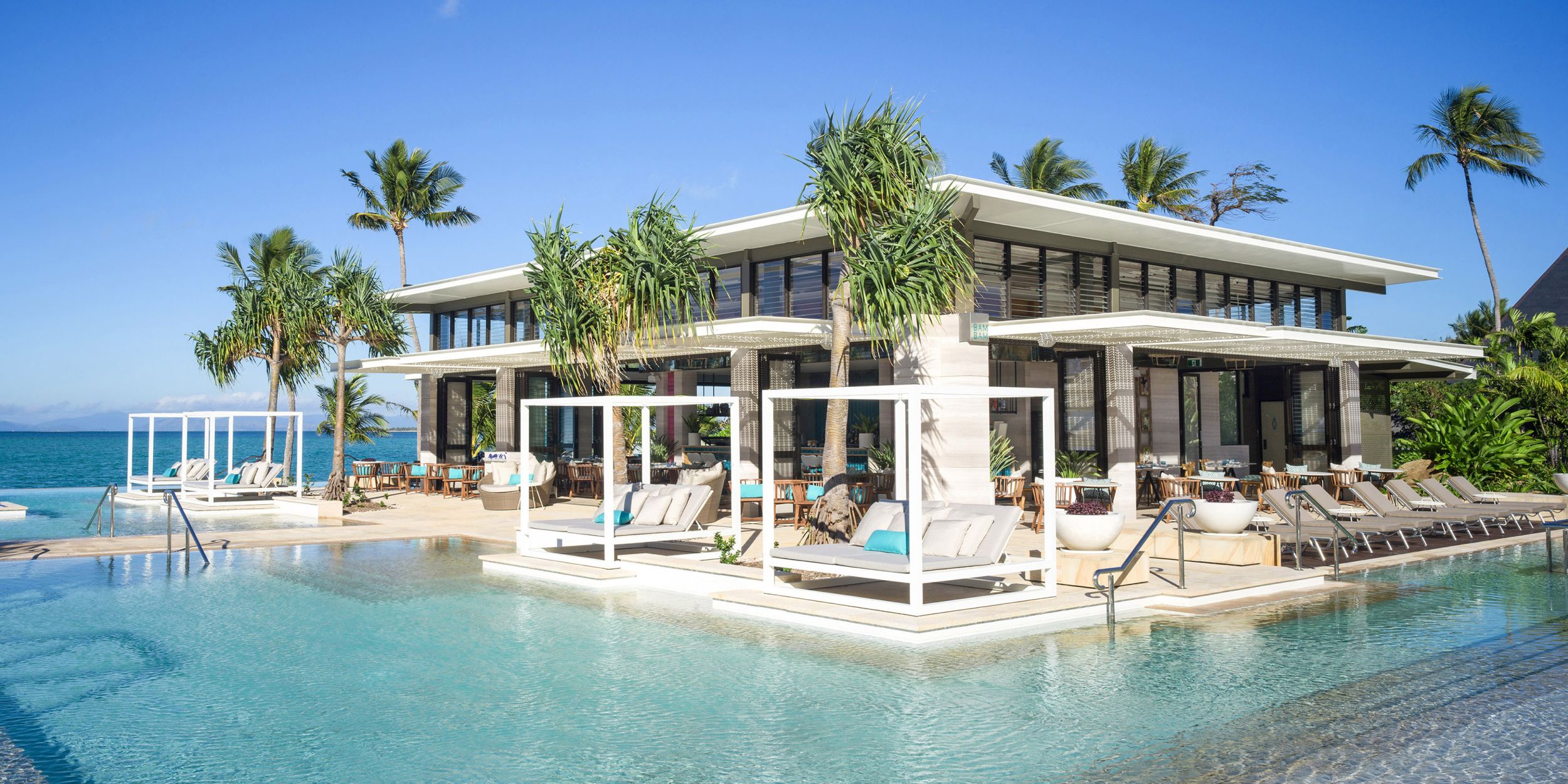 Beachfront resort with palm trees and poolside cabanas