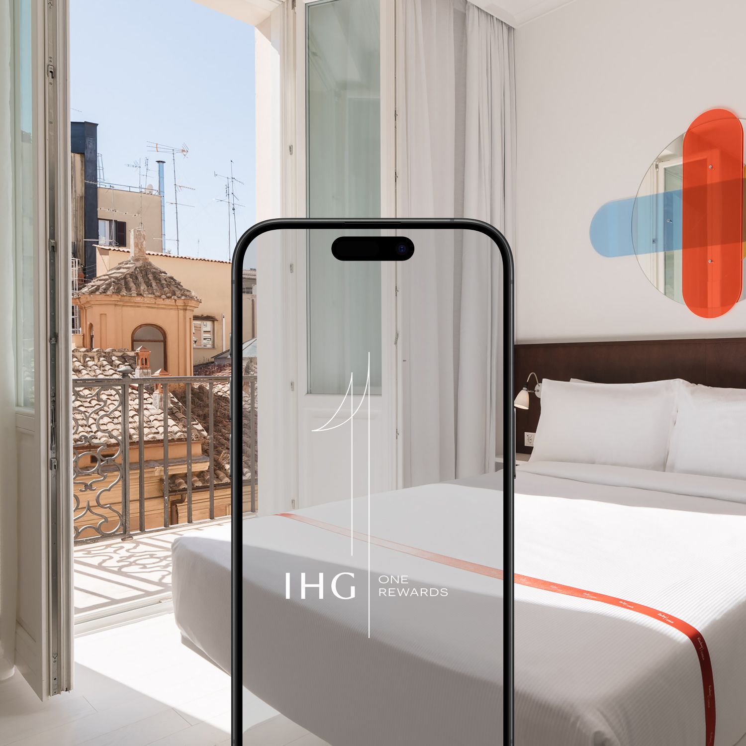 An image of a modern guest room at Ruby Giulia, with an IHG One Rewards mobile app frame in the middle