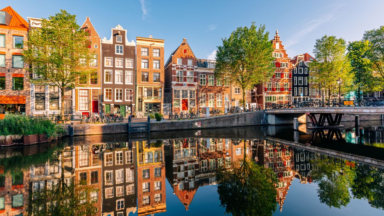 Amsterdam's canal houses lining the water, framed by autumn foliage