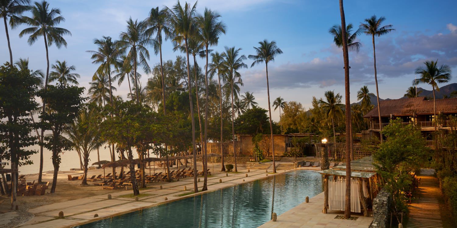 Outdoor pool next to the beach and surrounded by palm trees