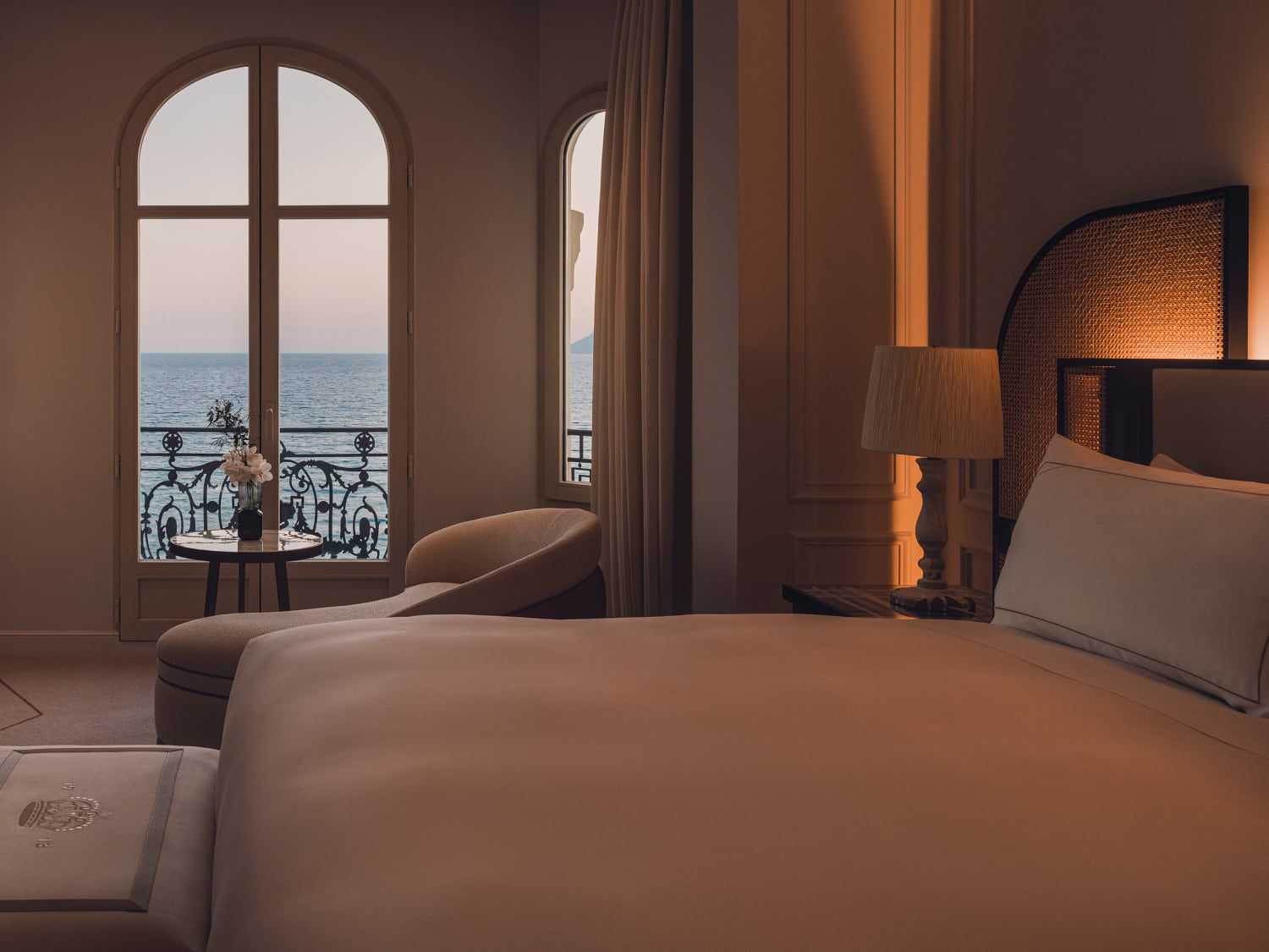 Hotel bedroom with warm ambient lighting, and a sunset view of the sea