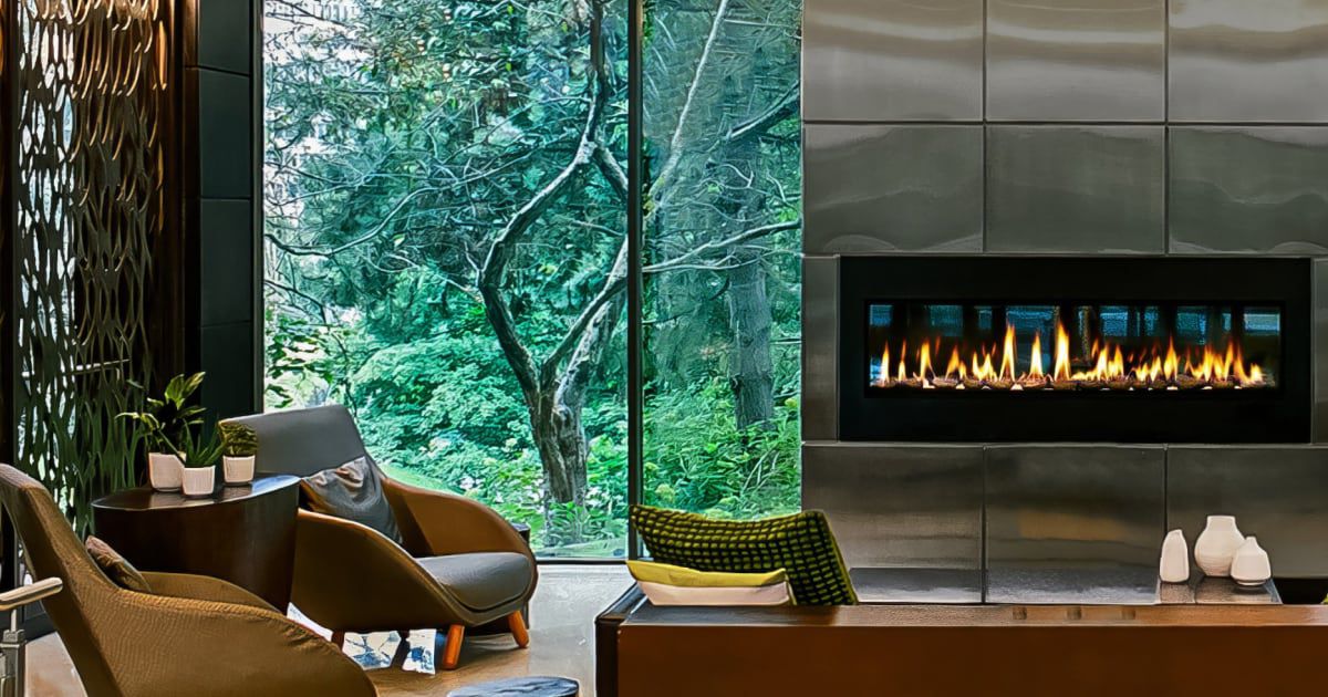Cozy lobby lounge with fireplace and window views of lush foliage.