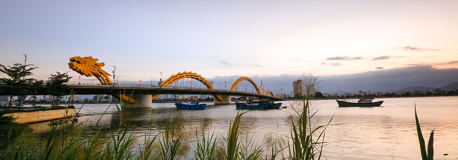 view of boats gliding along a river underneath the Dragon Bridge