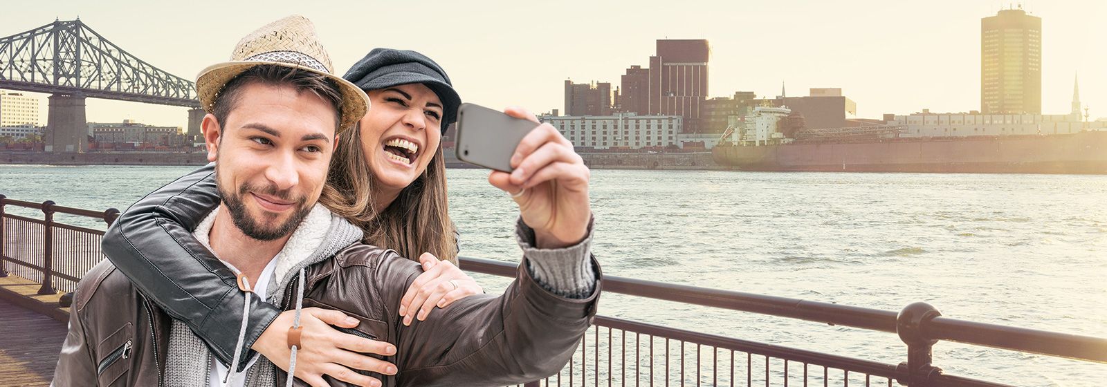 Couple taking a selfie with along the river with a cityscape in the background