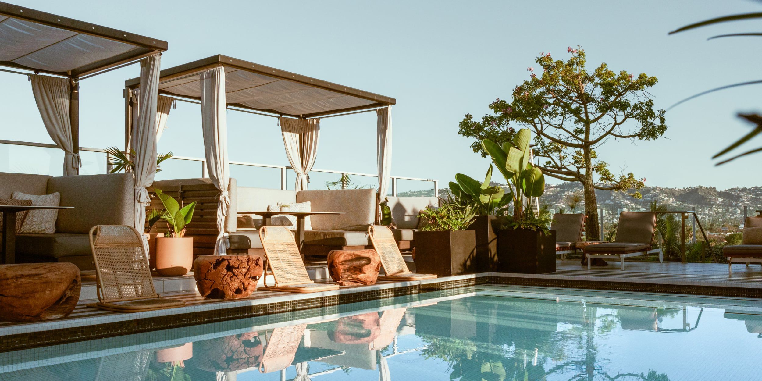 A rooftop pool deck with modern cabanas during golden hour