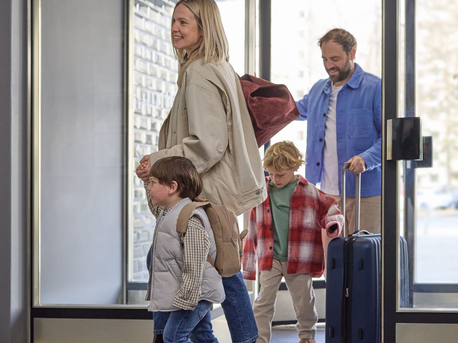 A family of four, Mom, Dad, and two young boys entering a Garner hotel lobby.