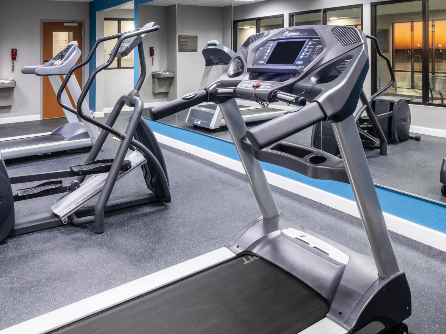 Một phòng gym rộng rãi với máy chạy bộ, máy tập elip và các thiết bị tập cardio khác.