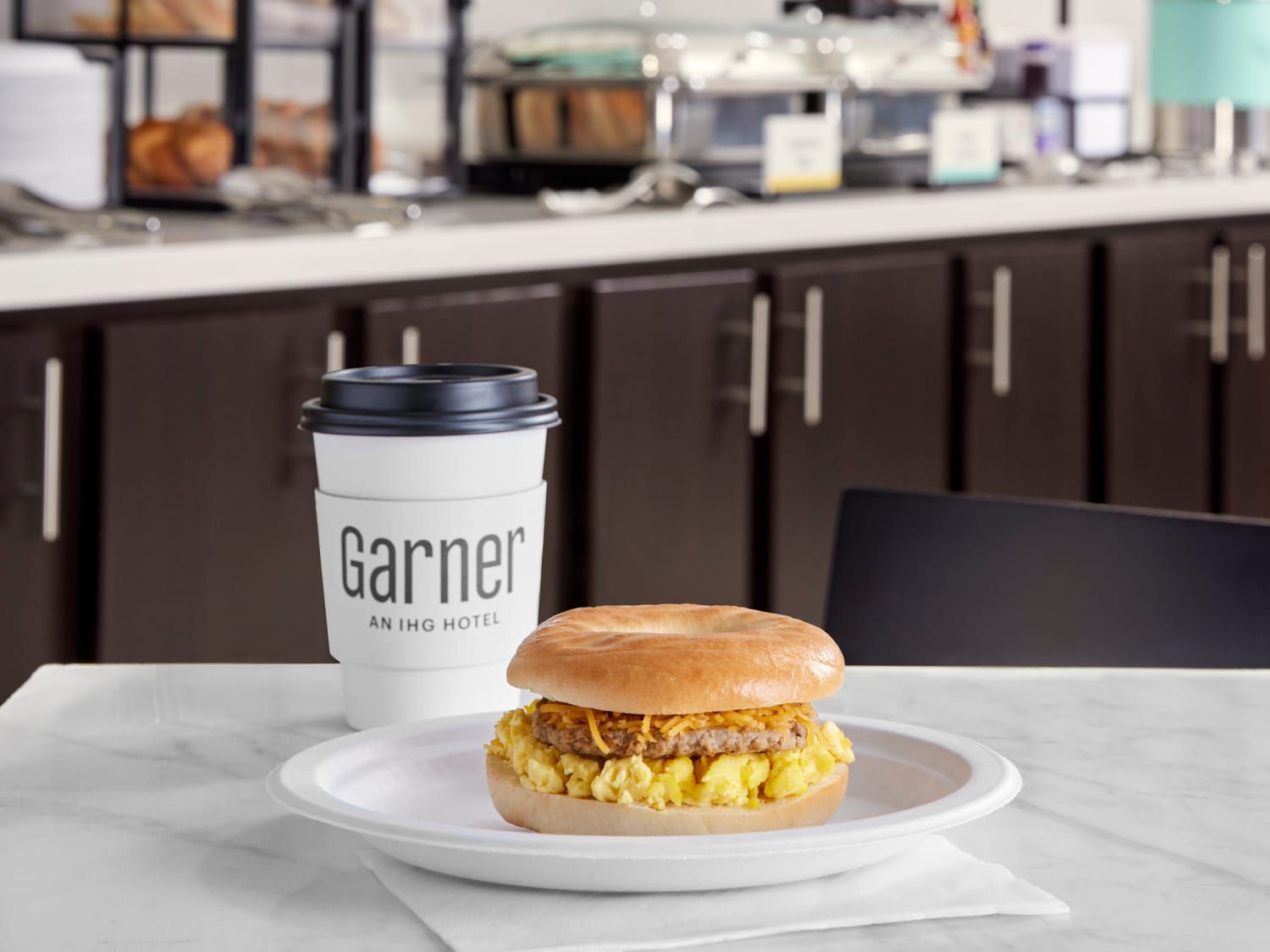 Bánh sandwich nóng hổi với xúc xích và trứng cho bữa sáng, cùng ly cà phê nguyên chất từ hạt mới làm để mang đi.