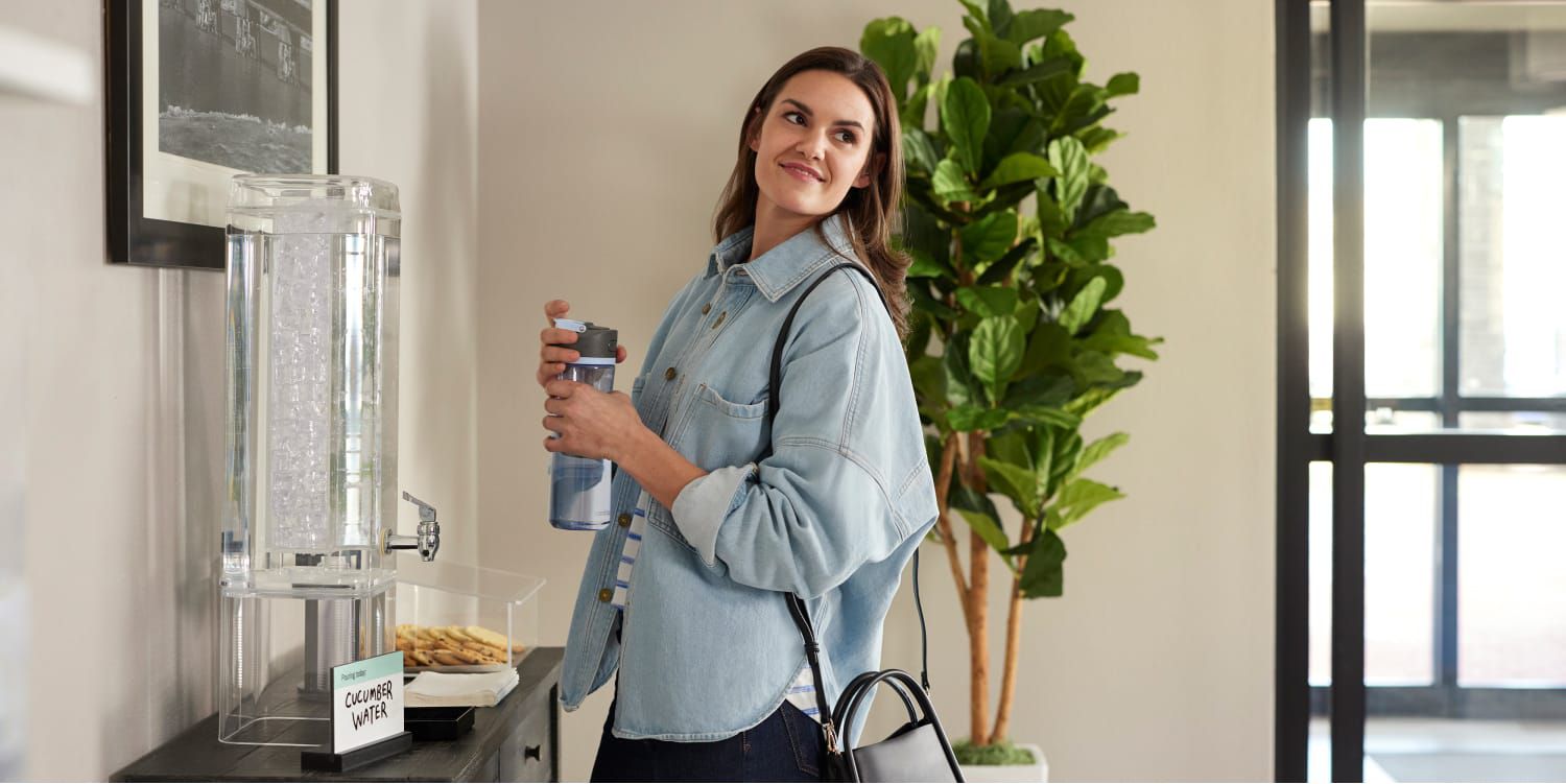 Woman refilling water bottle at flavored water station