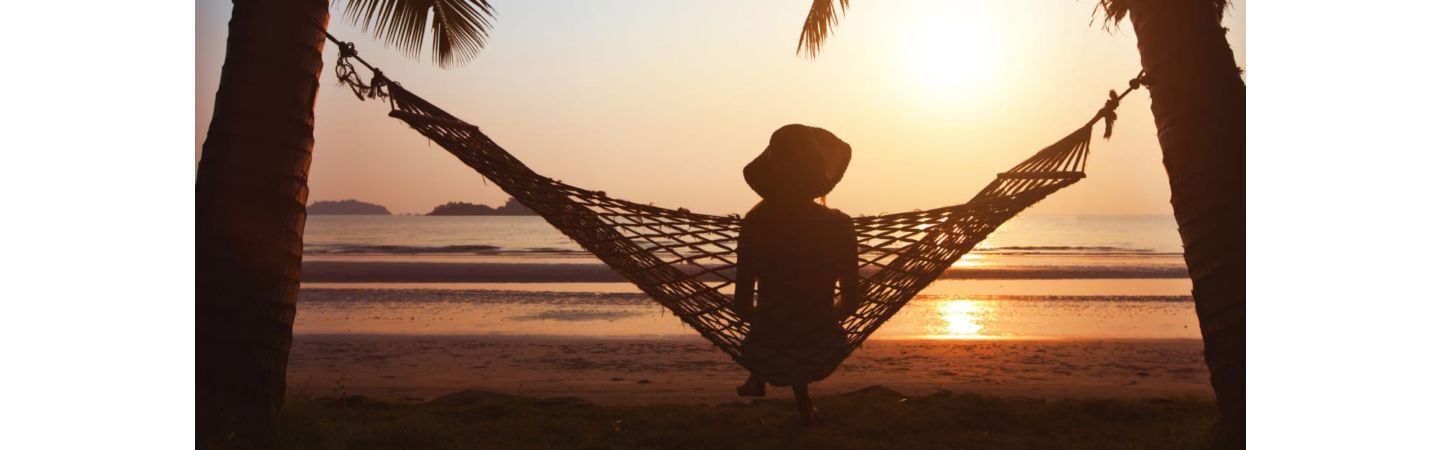 Beach sunset with person sitting in a hammock