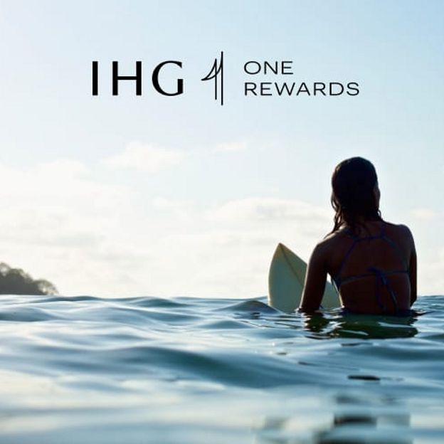 Imagen de una mujer de IHG One Rewards surfeando con el logotipo de IHG One Rewards