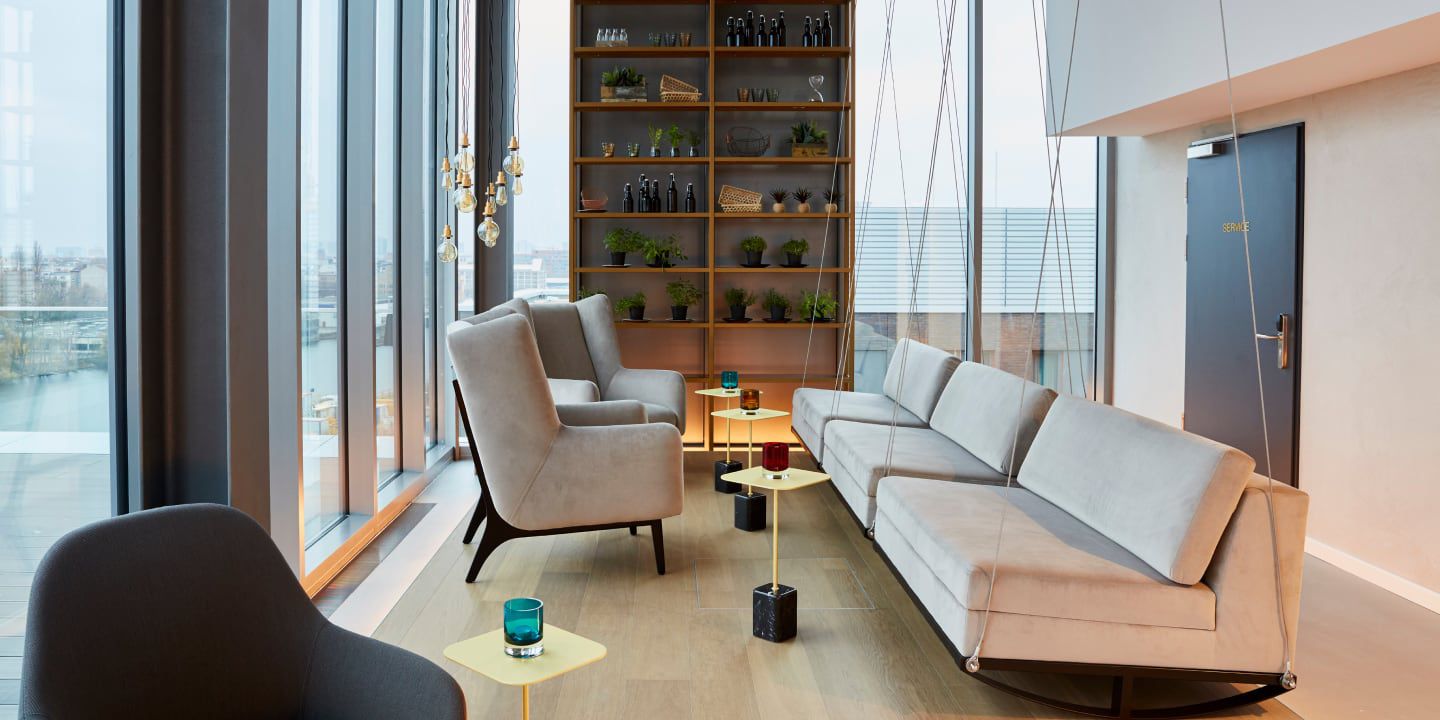 Modern lounge with large windows, beige seating, and decor.