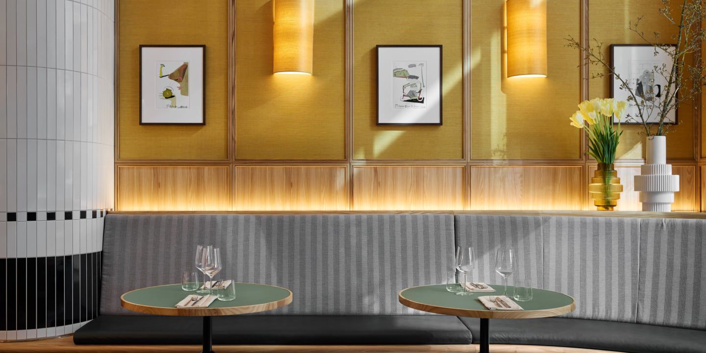 Chic restaurant seating with striped bench, art, and flowers.