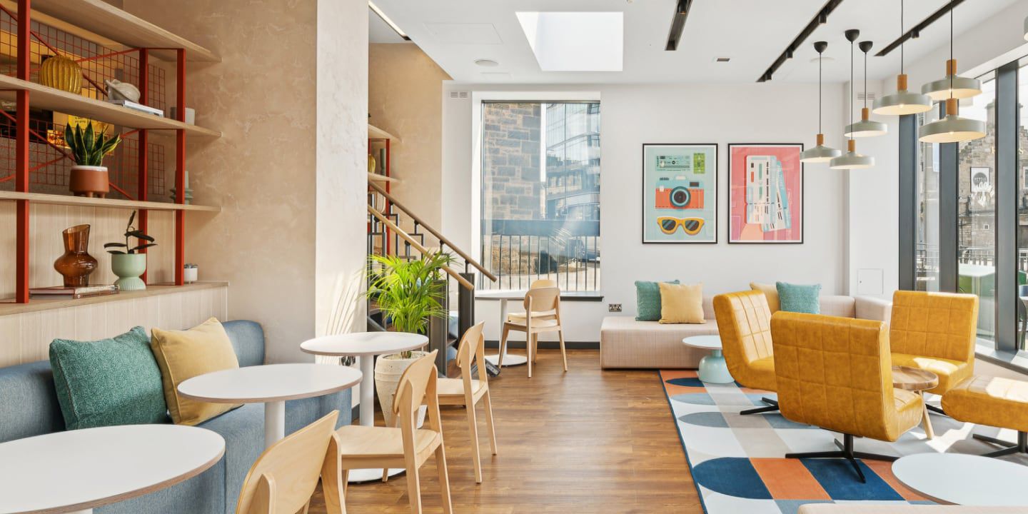 Bright café with colorful chairs, patterned rug, and large windows.