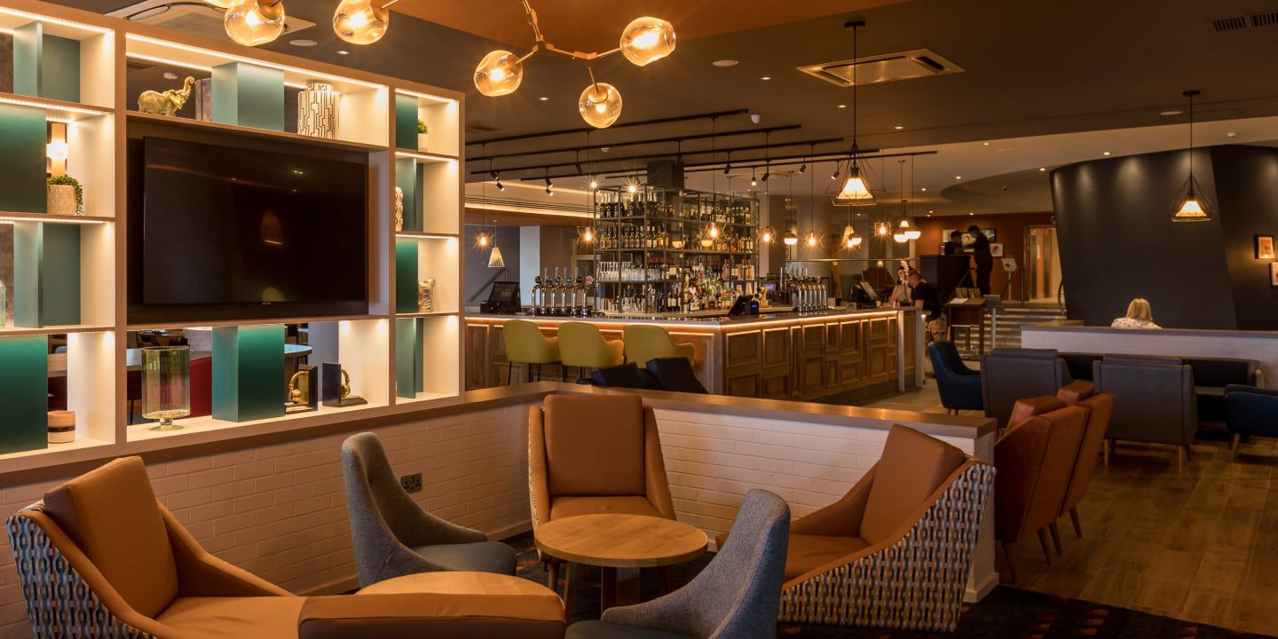 Modern hotel lounge with cozy seating, warm lighting, and TV.
