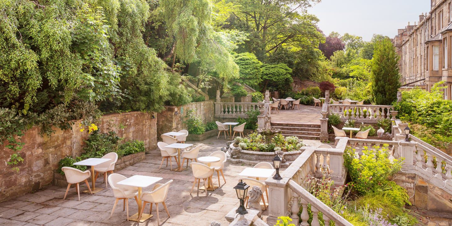Charming outdoor patio with garden views and white café tables.