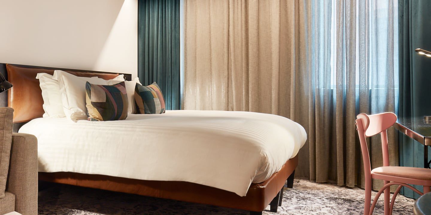 Cozy hotel room with bed, pillows, curtains, and chair.