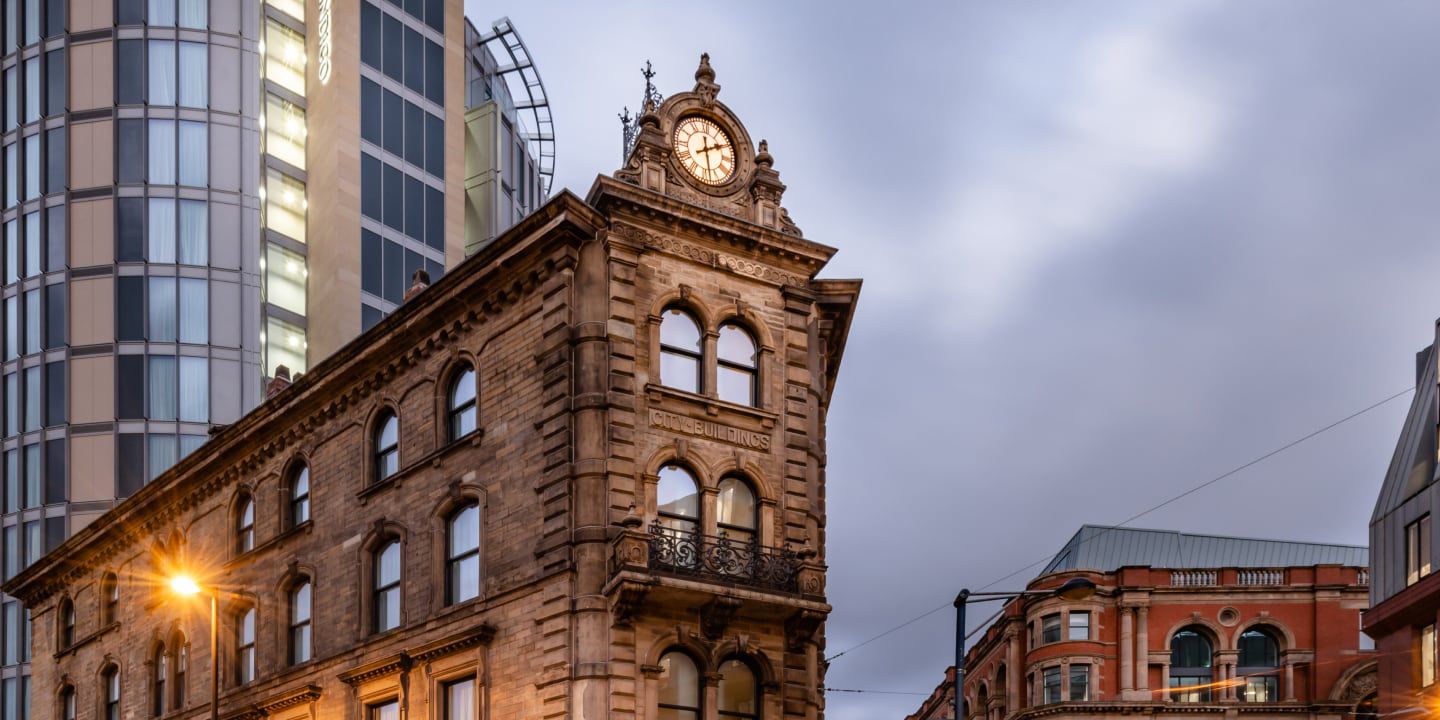 Historic stone building with clock tower in city at dusk.