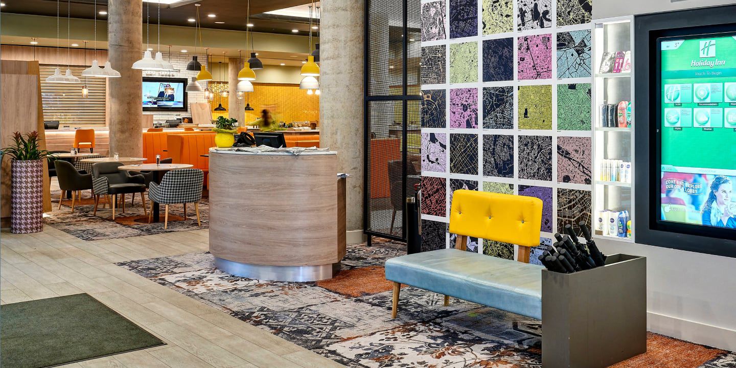 Colorful modern lobby with seating area, wall art, and kiosk.