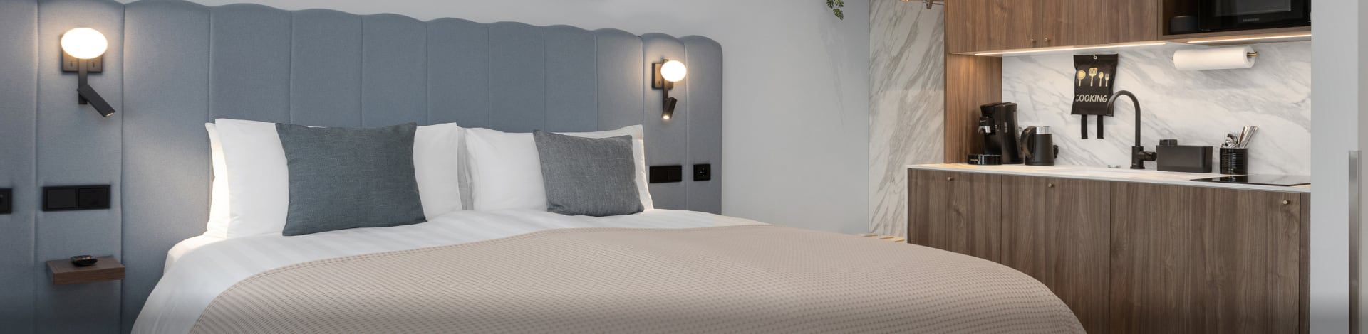 A room at Candlewood Suites Reykjavik with a gray scalloped headboard and a kitchenette.