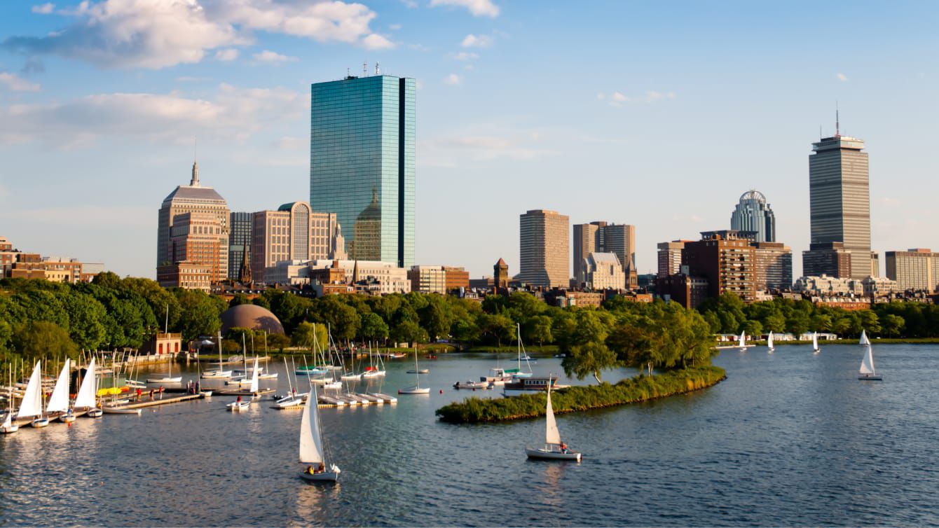 Sailboats glide along the Charles River with the Boston skyline in the background.