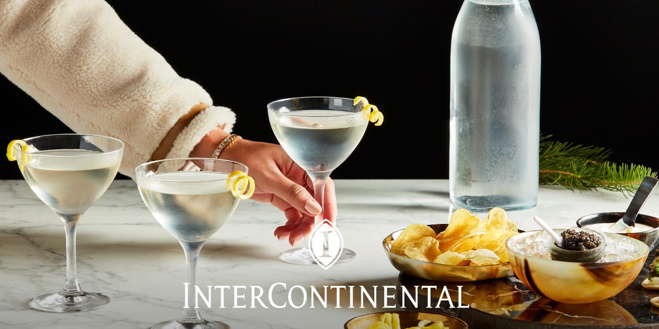 a person reaching for a cocktail on a marble table with caviar and wintery decor