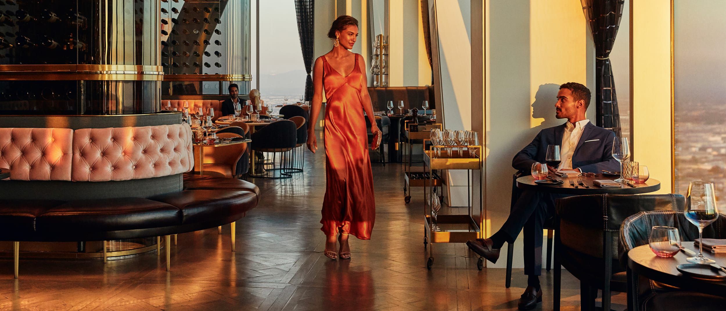 An elegant dining room and lounge with a couple in the golden hour light.