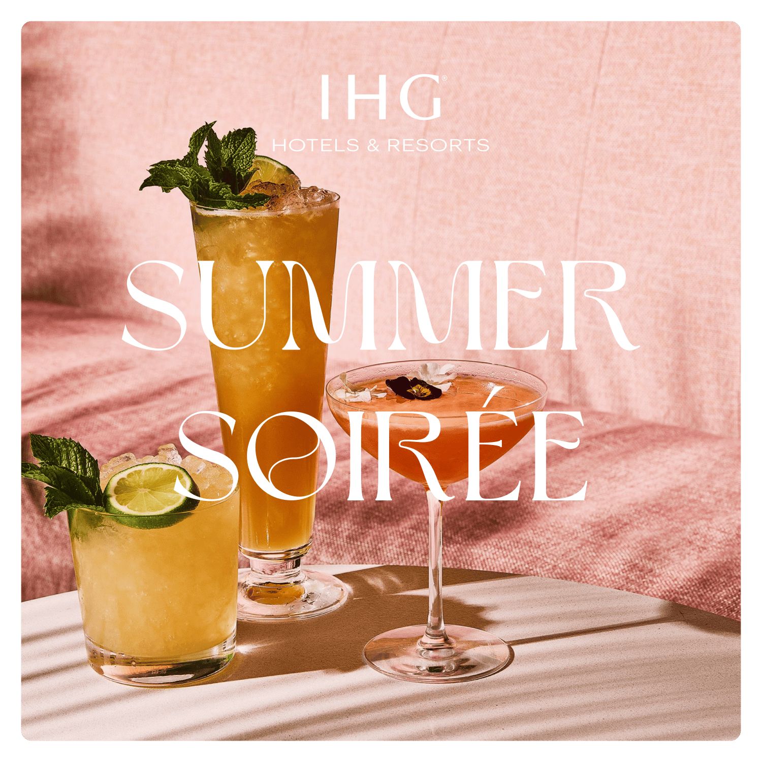 three cocktails on a table in front of a pink couch in the sun