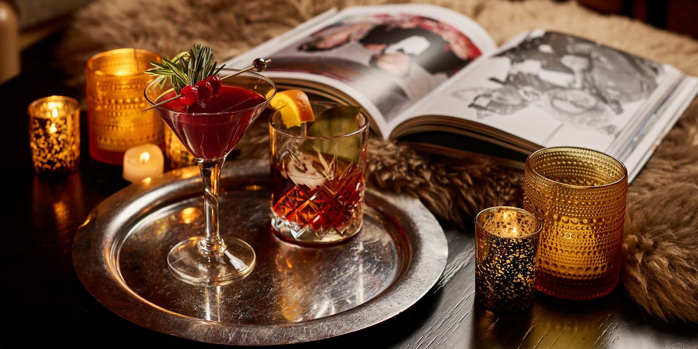 close up of cocktails on a tray with candles and an open book