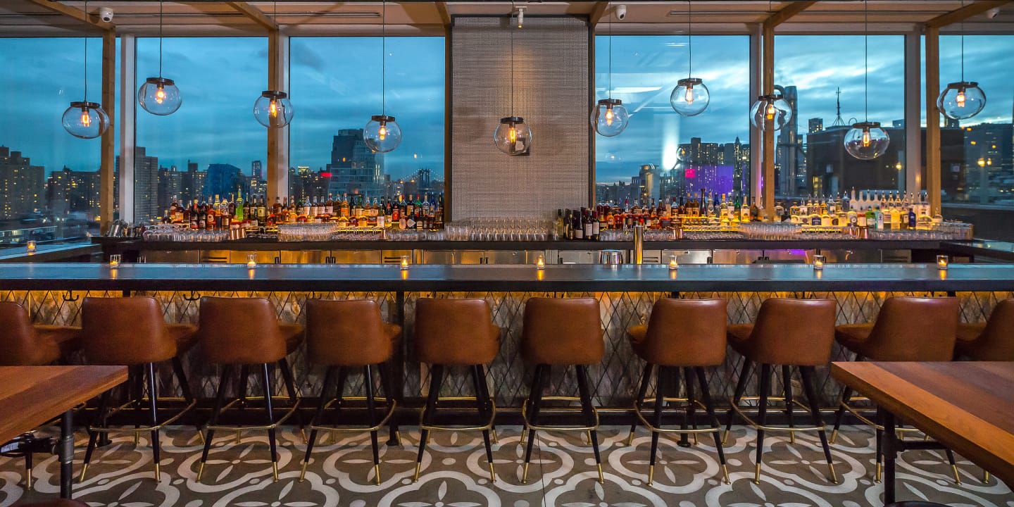expansive bar with leather seats overlooking evening city skyline