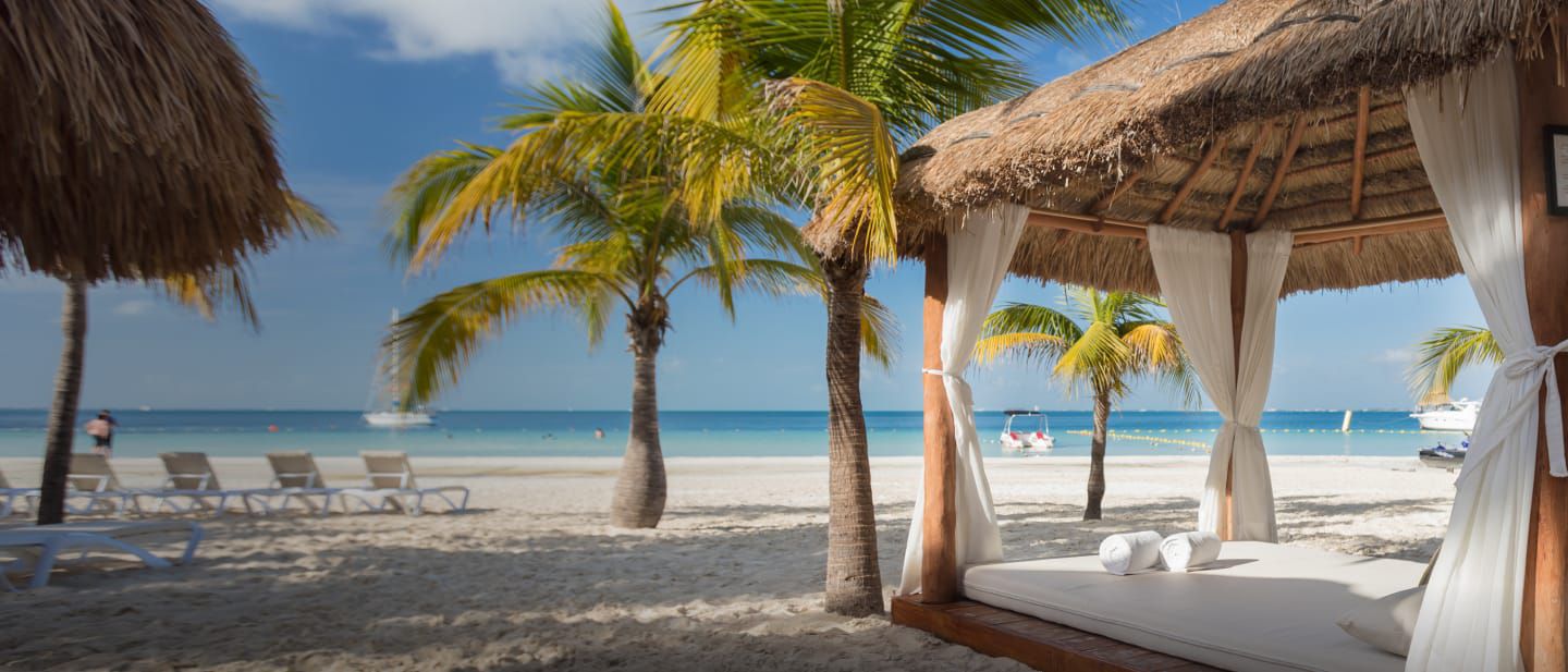 Private cabanas and chairs on a white sands beach overlooking clear ocean waters