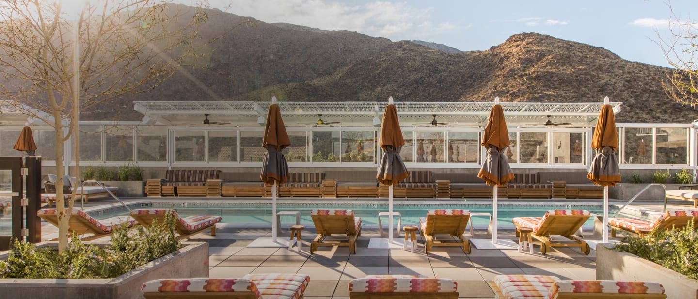Line of pool chairs overlooking a pool and mountainscape