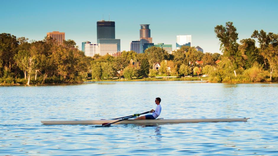 Person rowing a kayak on city-side lake