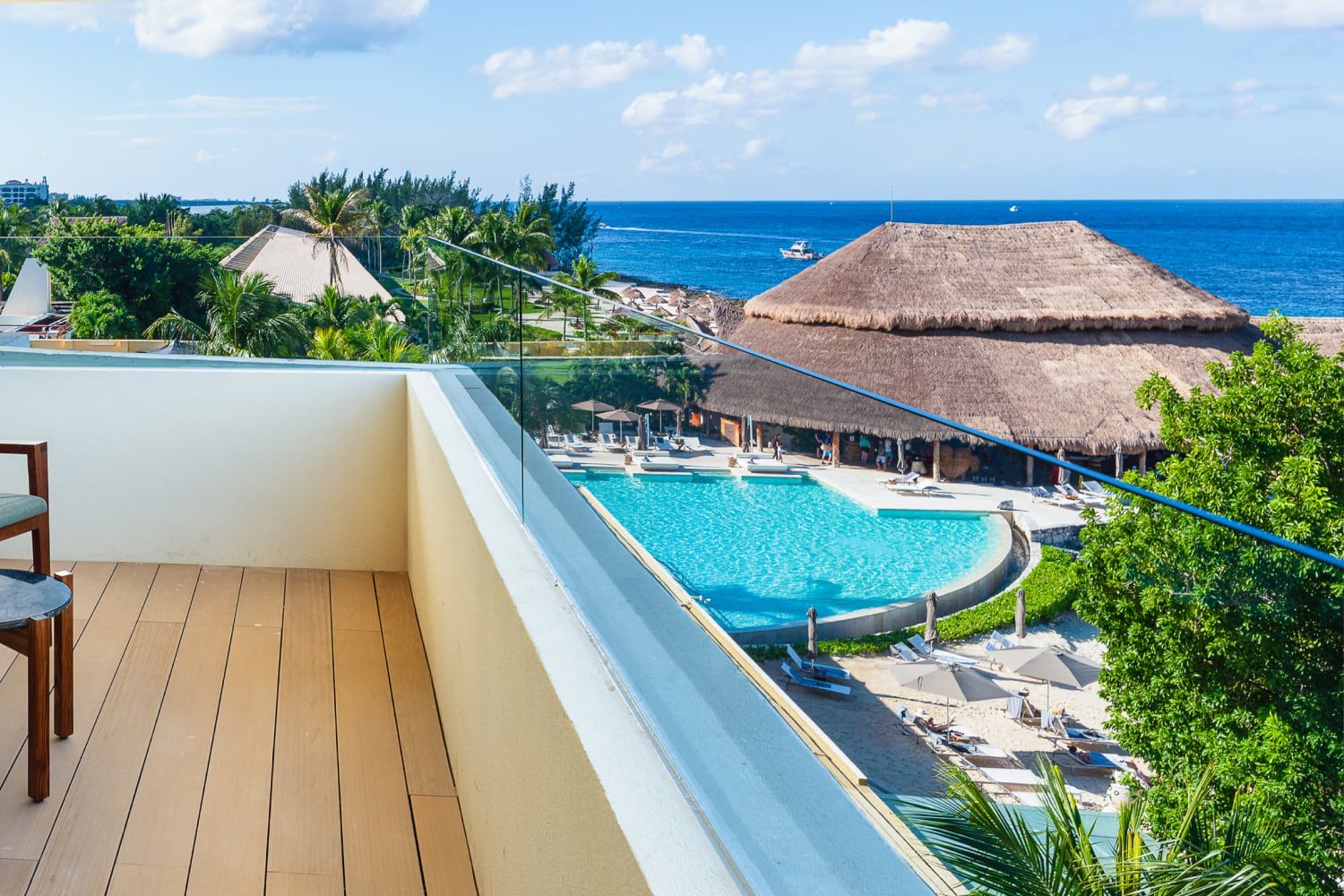 Piscina tropical y vista al mar desde un balcón en la Riviera Maya