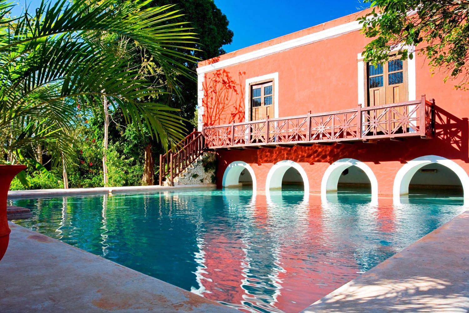 Fachada de color naranja oscuro con vistas a la piscina en Mérida