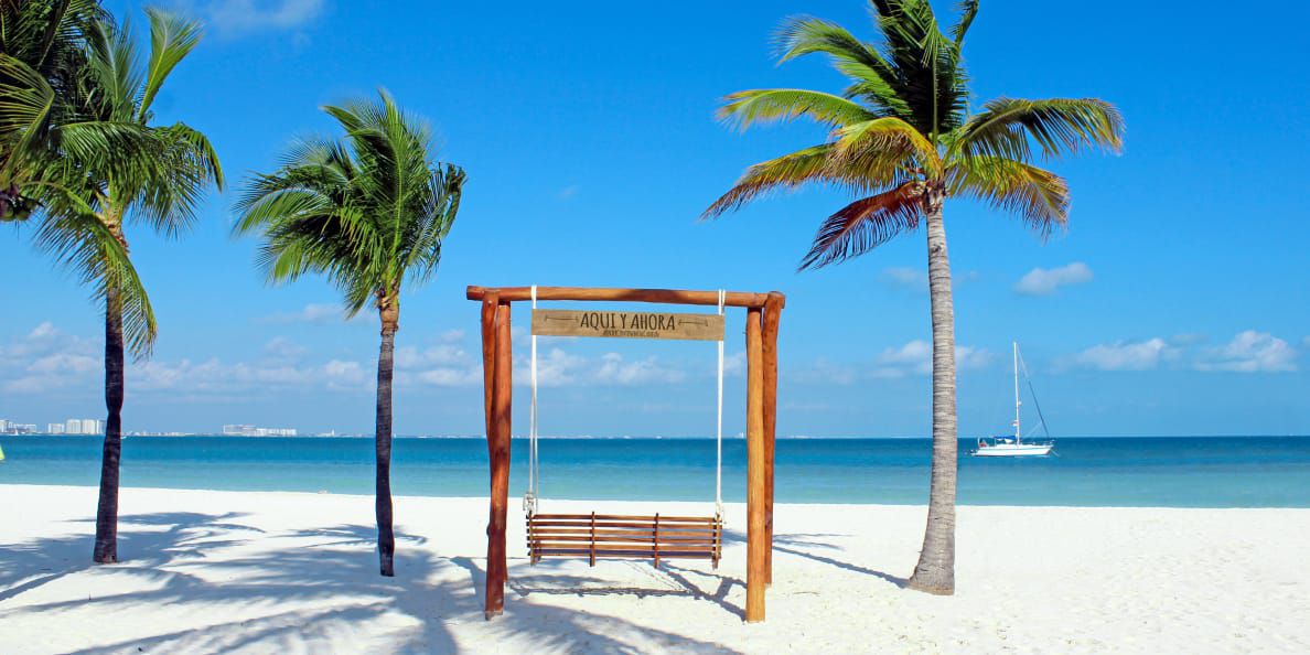 Wooden swing on white sandy beach overlooking the ocean