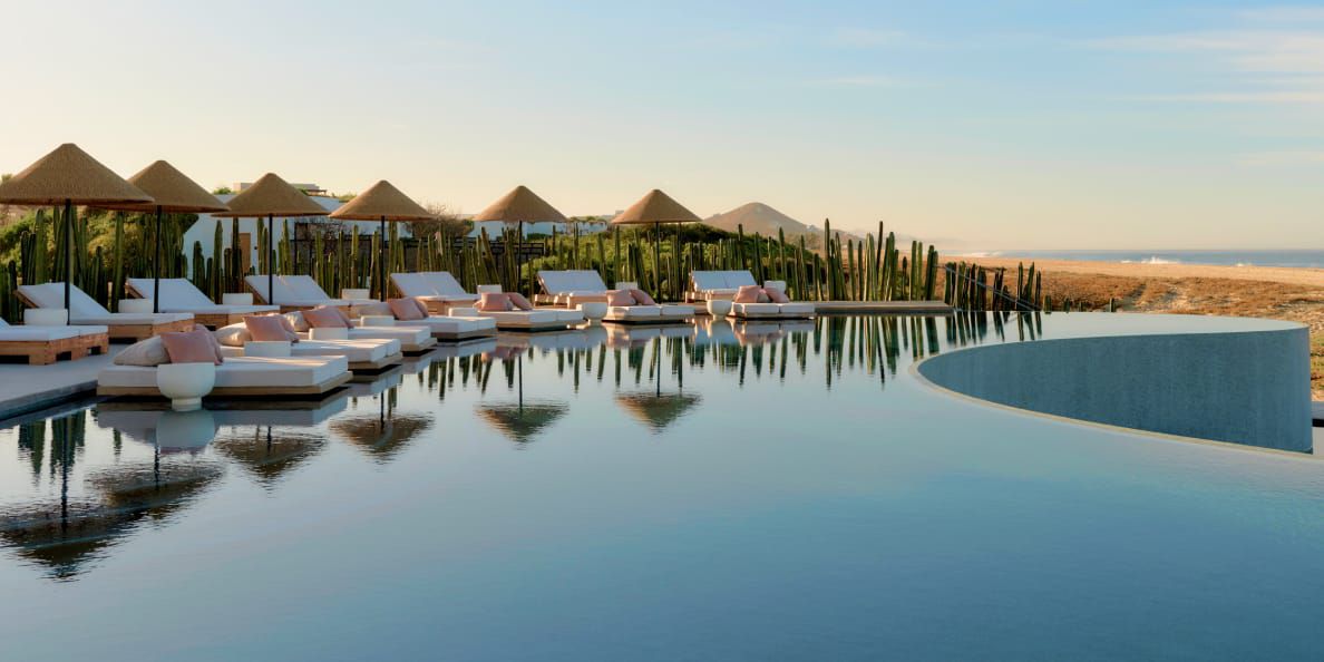 Infinity pool with poolside beds reflecting on the water