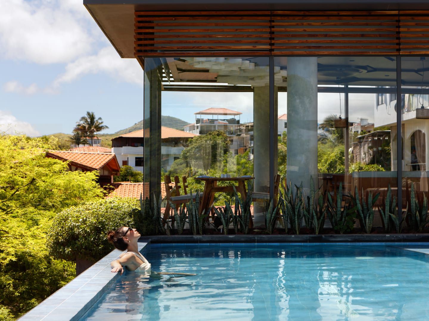 Woman sunbathing in modern pool overlooking lush hillside