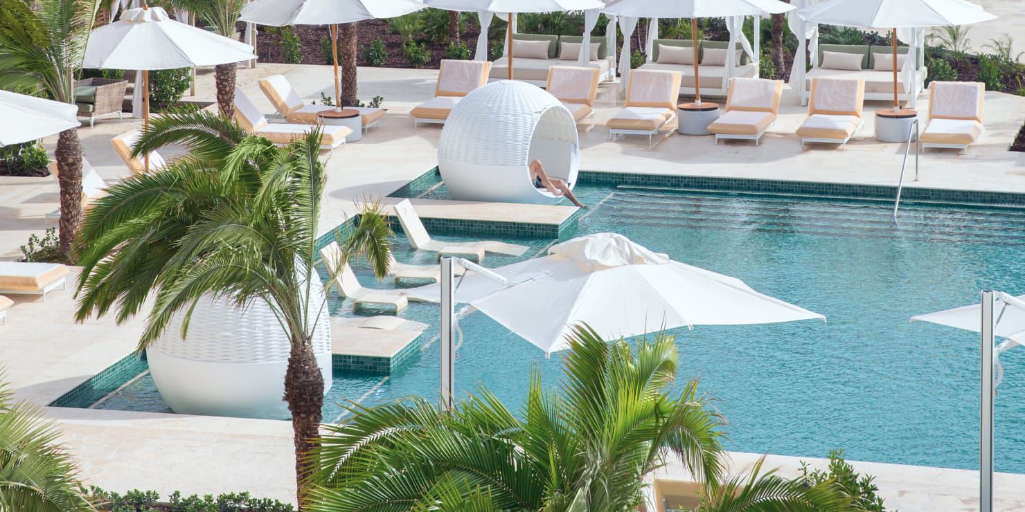 Pool surrounded by cabana seating and palm trees