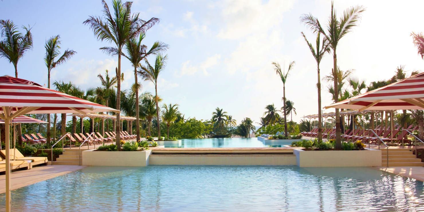 Two-tiered pool lined with chairs and palm trees
