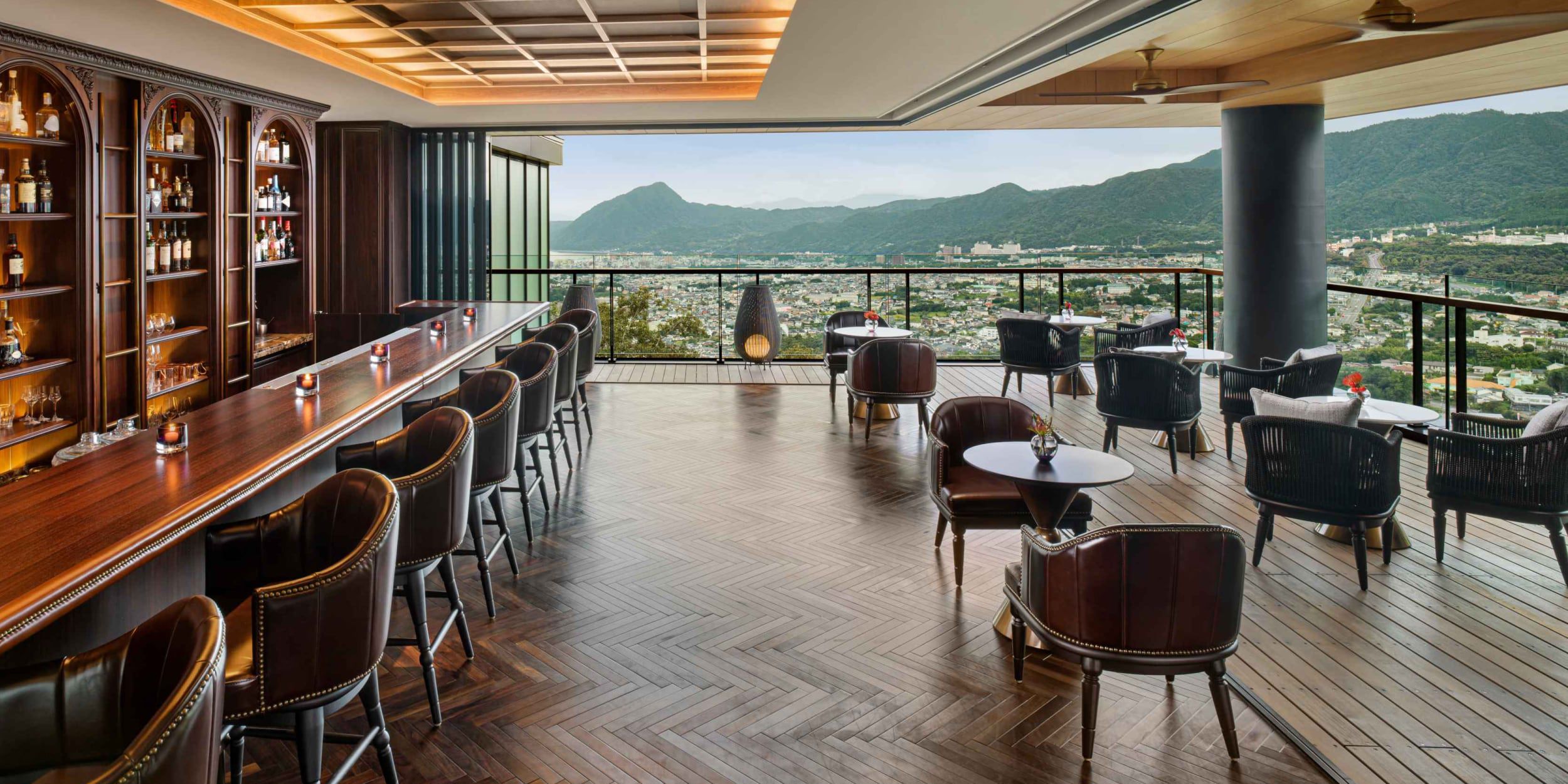 A covered outdoor bar overlooking mountains and a city near