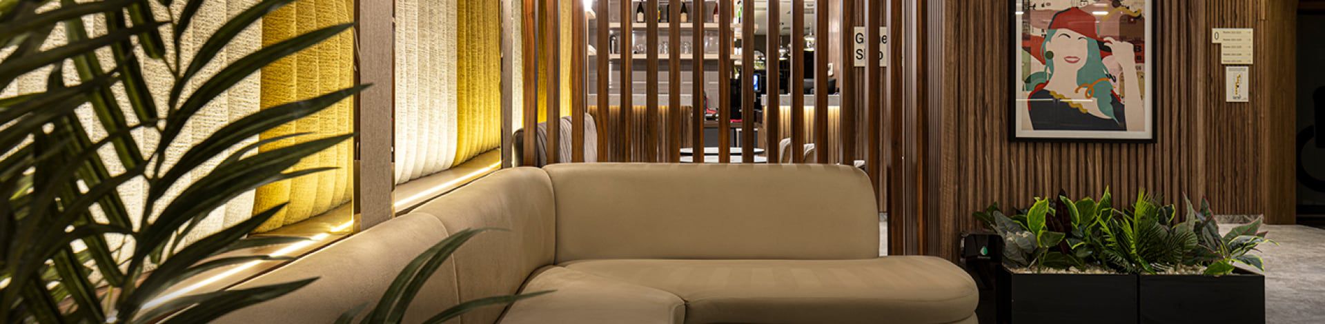Wood-paneled hotel sitting area with tropical plants and art