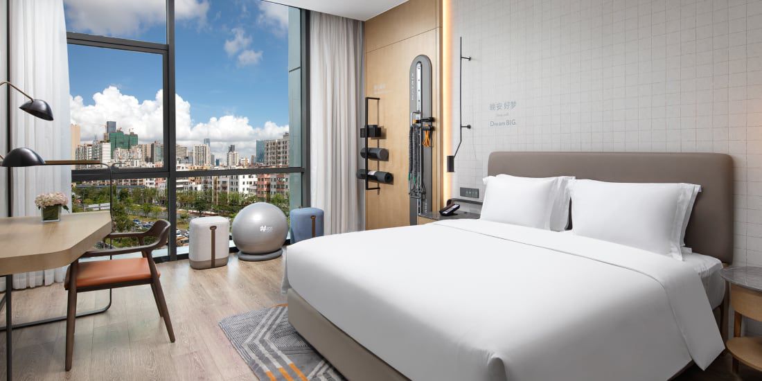 Guest bed, in-room fitness zone, and city views at EVEN Hotel Shenzhen Nanshan