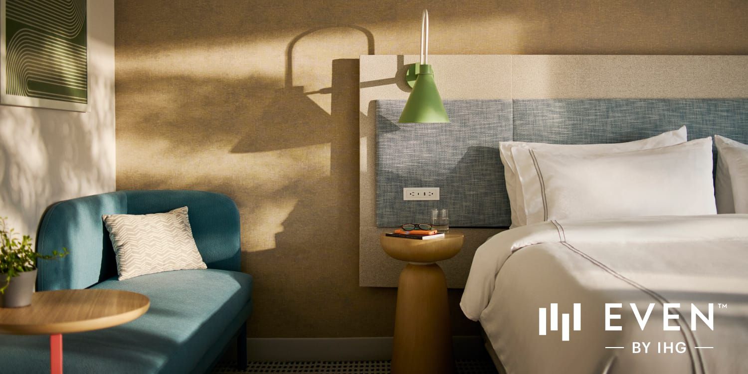 Modern hotel room with crisp white bedding and shadows cast on the wall.